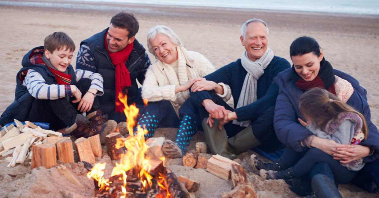 Grandparents, parents, and children connect by enjoying time together around a beach bonfire. Grandparents, parents, and children connect by enjoying time together around a beach bonfire.