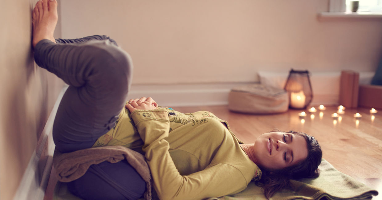 A woman does yoga in her meditation corner, surrounded by lit candles. A woman does yoga in her meditation corner, surrounded by lit candles.