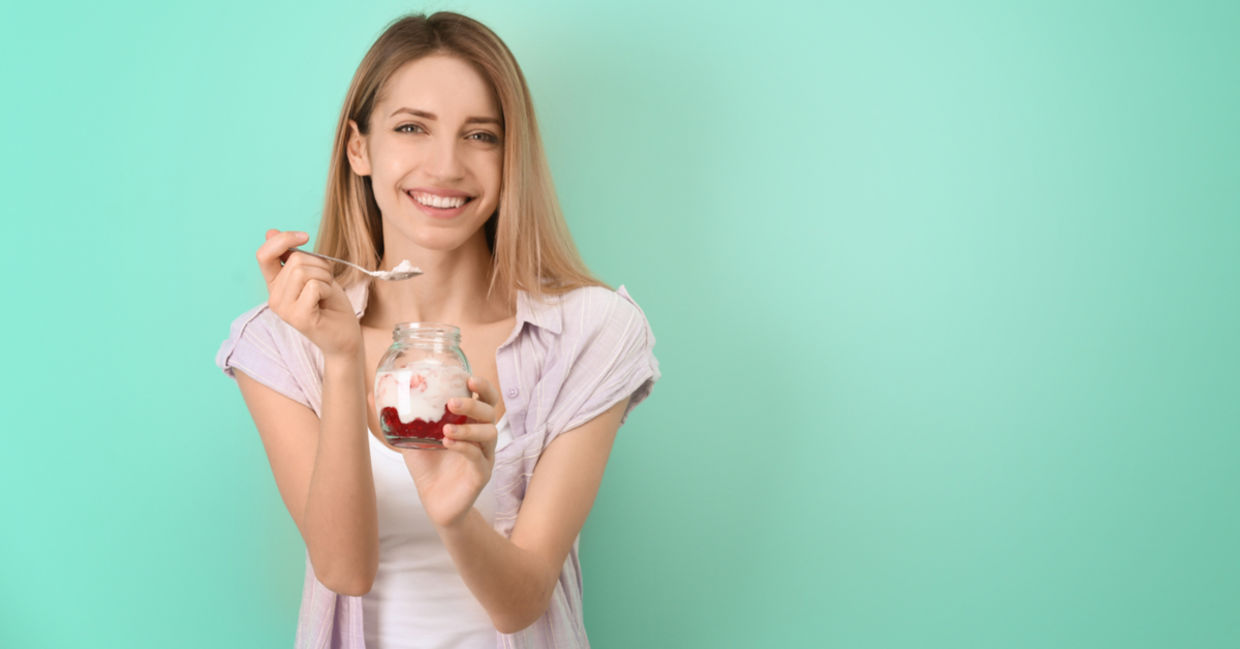 A young woman is eating a gut-healthy breakfast of yogurt with fruit. A young woman is eating a gut-healthy breakfast of yogurt with fruit.