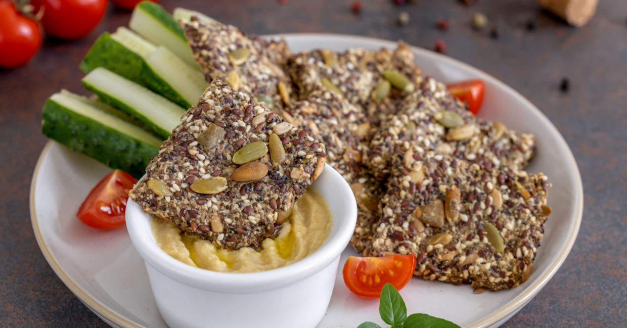 Homemade seed crackers are served with hummus and fresh vegetables. Homemade seed crackers are served with hummus and fresh vegetables.