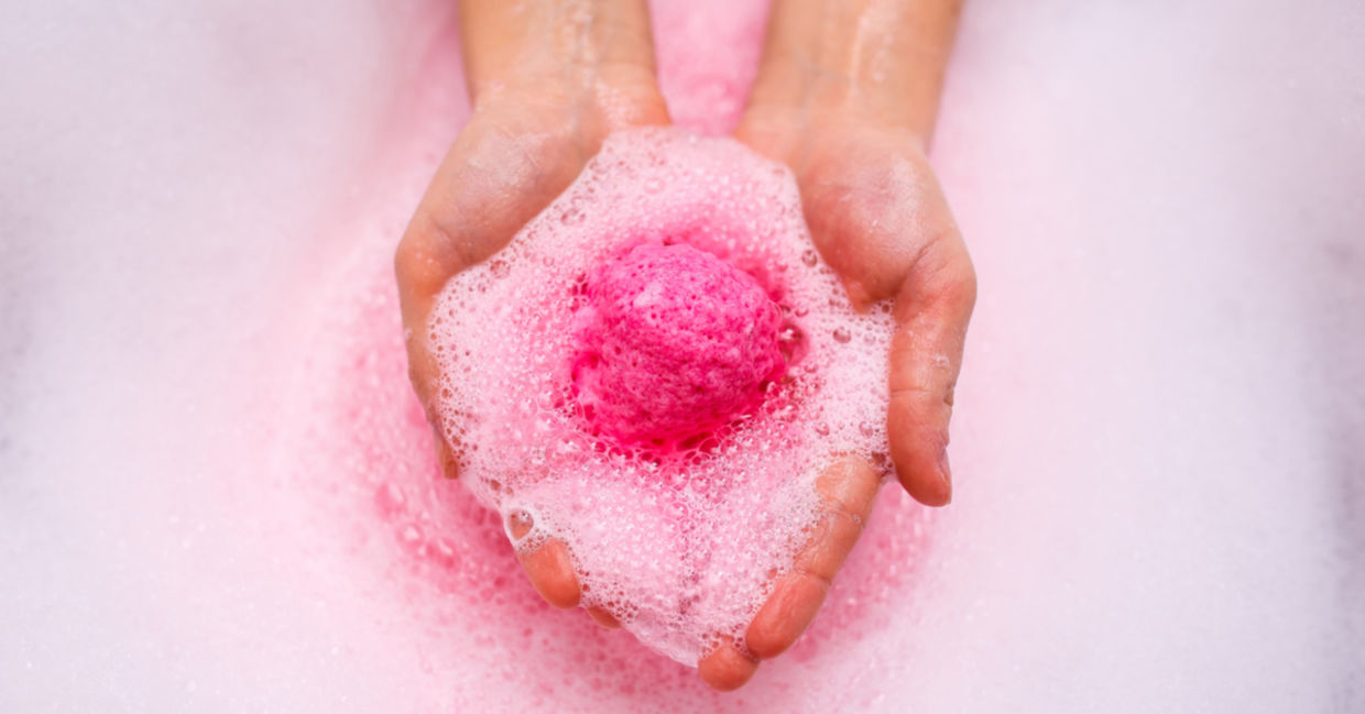 A pink shower steamer dissolves in a woman’s hands. A pink shower steamer dissolves in a woman’s hands.