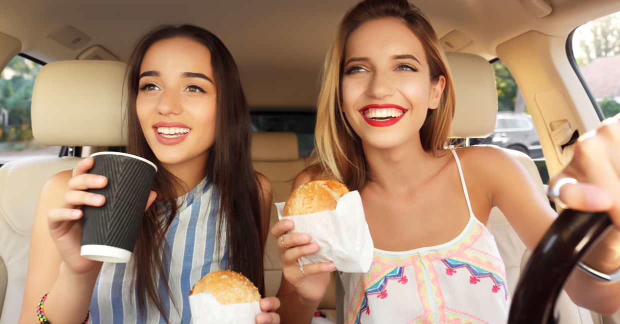Young women eating fast food in a car. Young women eating fast food in a car.