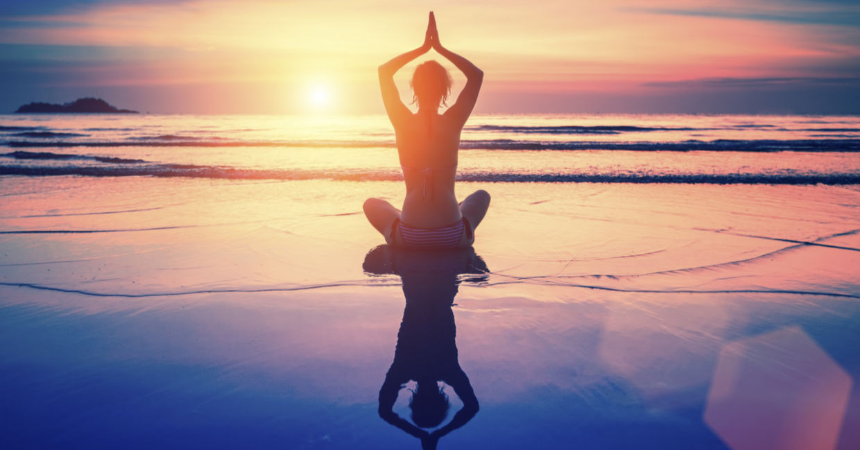 A woman meditates on the beach at sunset. A woman meditates on the beach at sunset.