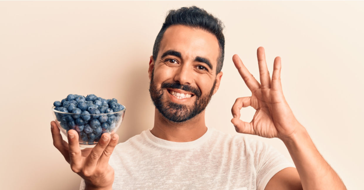 A man holds a bowl of gut-friendly blueberries. A man holds a bowl of gut-friendly blueberries.