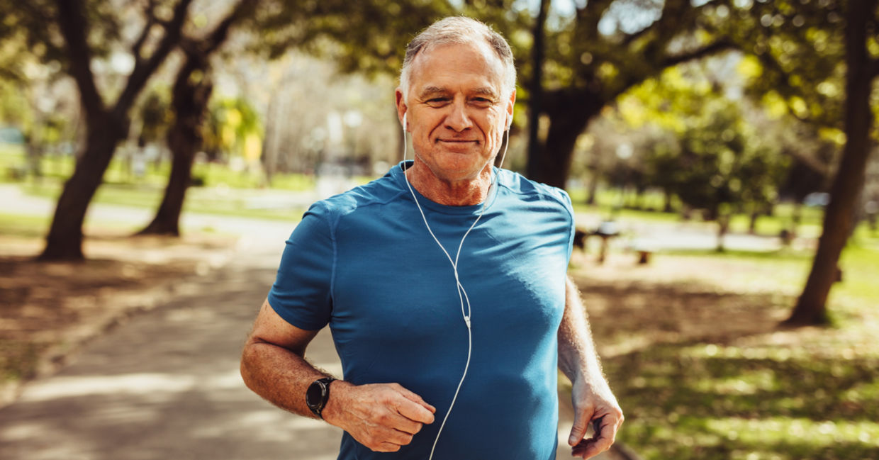 A man smiles as he jogs in a park. A man smiles as he jogs in a park.