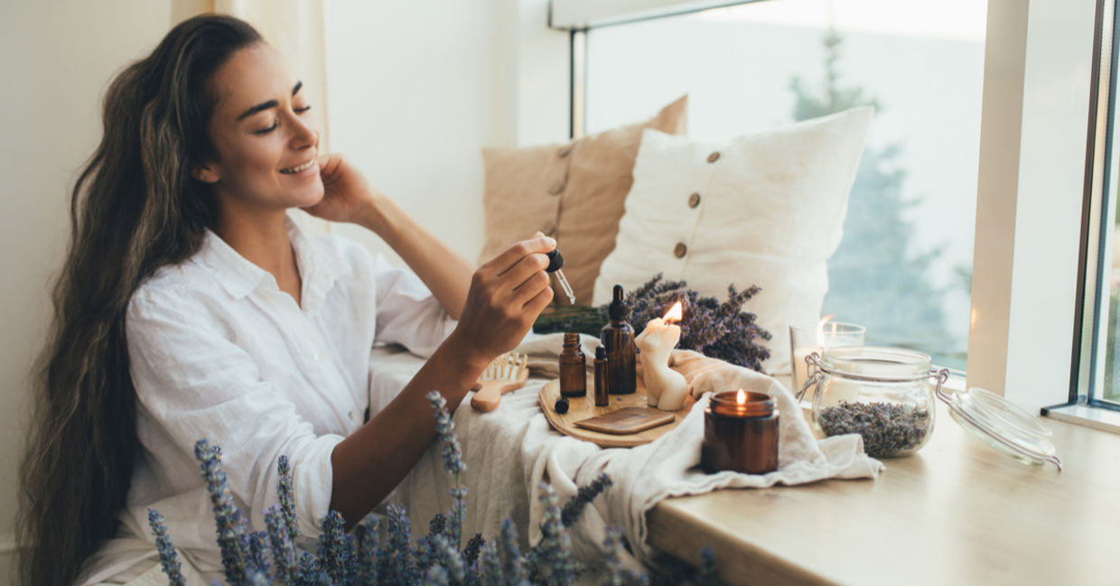 Woman applying essential lavender oil to her hair as part of her beauty ritual. Woman applying essential lavender oil to her hair as part of her beauty ritual.