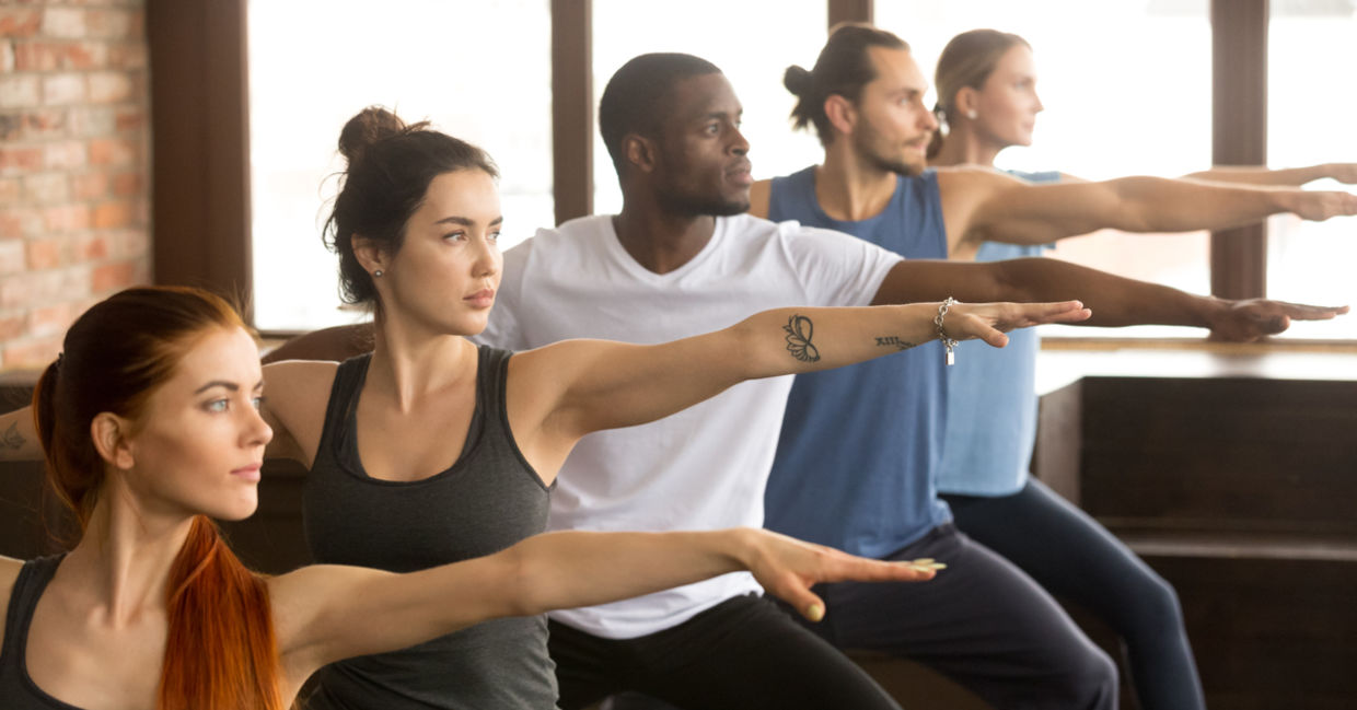 Yoga class in Warrior II yoga pose. Yoga class in Warrior II yoga pose.