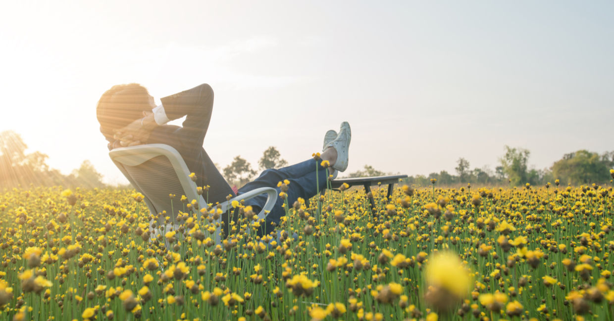 Businessman sitting in an office armchair and relaxing in a yellow flower field. Businessman sitting in an office armchair and relaxing in a yellow flower field.