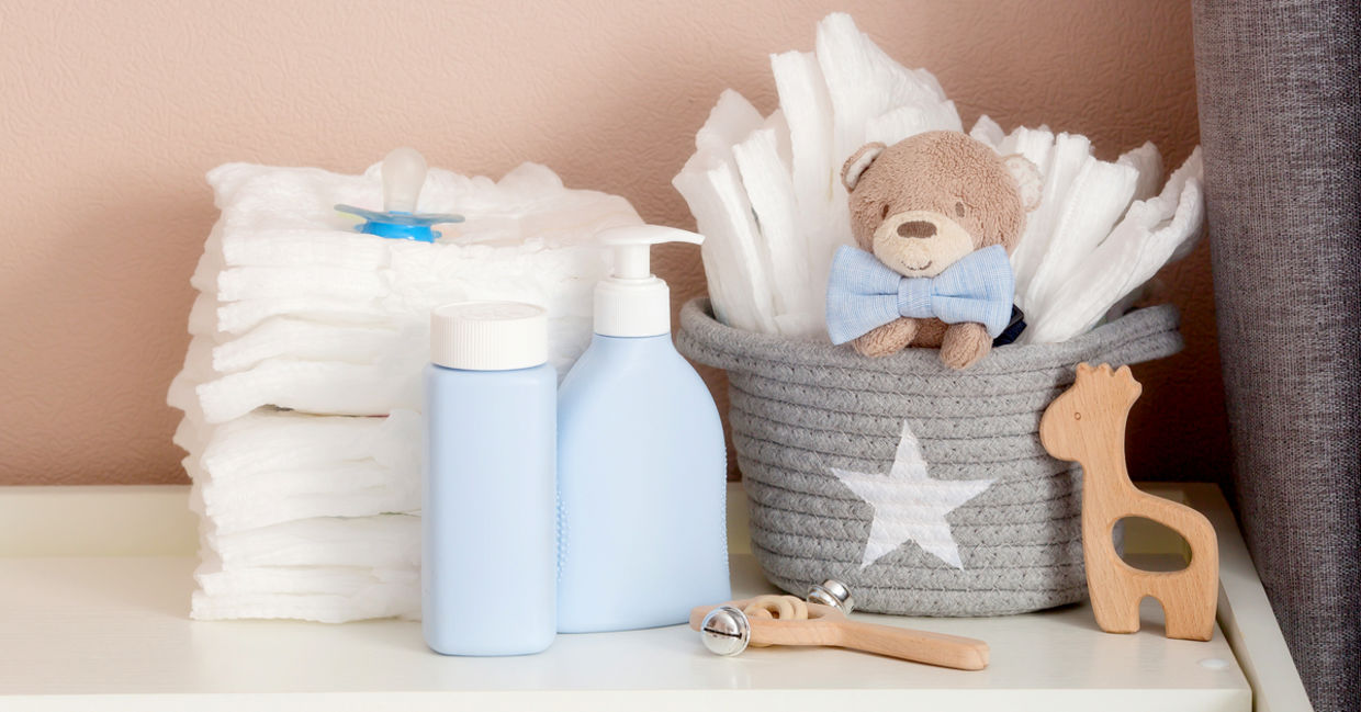 A stack of diapers, toys and baby accessories on a changing table. A stack of diapers, toys and baby accessories on a changing table.