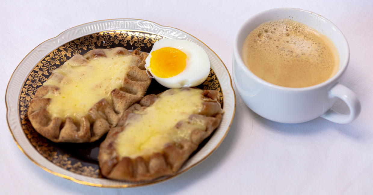 Cup of coffee and Traditional Finnish Karelian pies on a plate. Cup of coffee and Traditional Finnish Karelian pies on a plate.