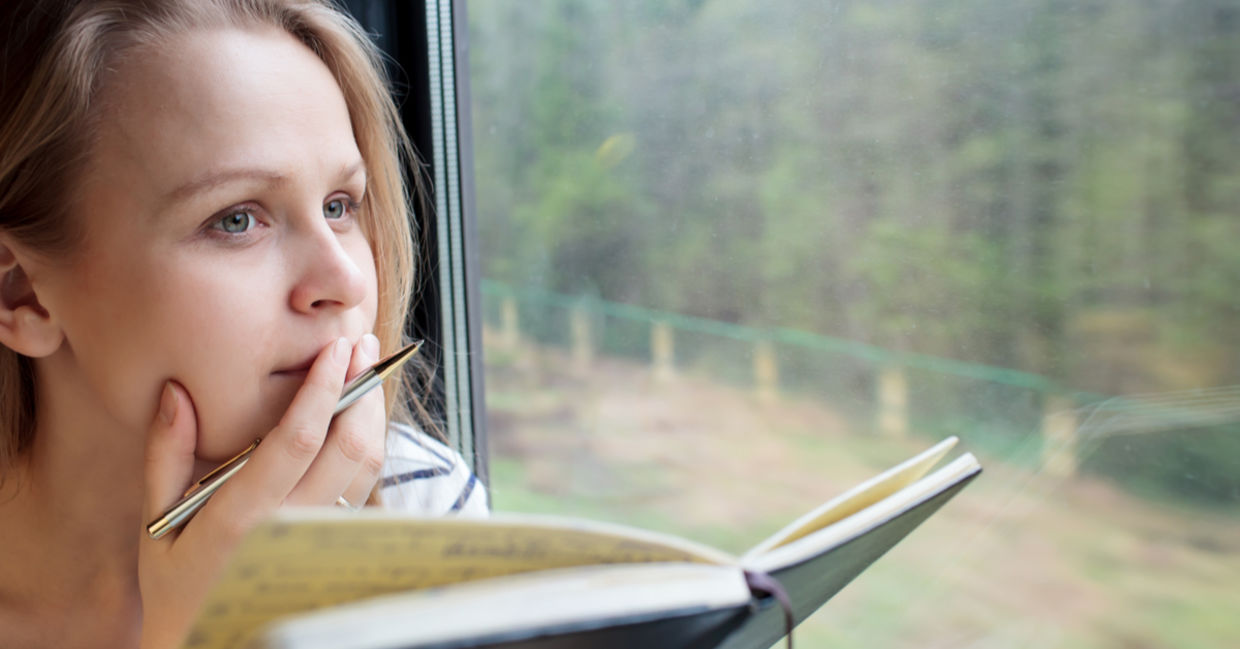 Woman on a train thinking about what to add to her journal. Woman on a train thinking about what to add to her journal.