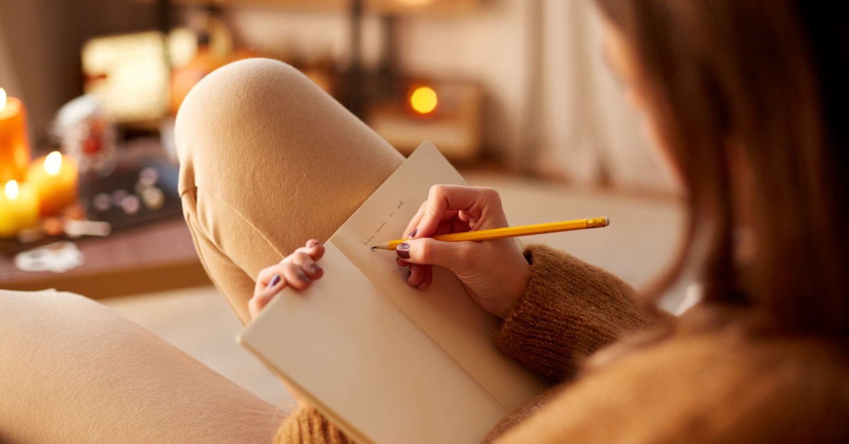 Woman writing in diary while relaxing in her cozy home. Woman writing in diary while relaxing in her cozy home.