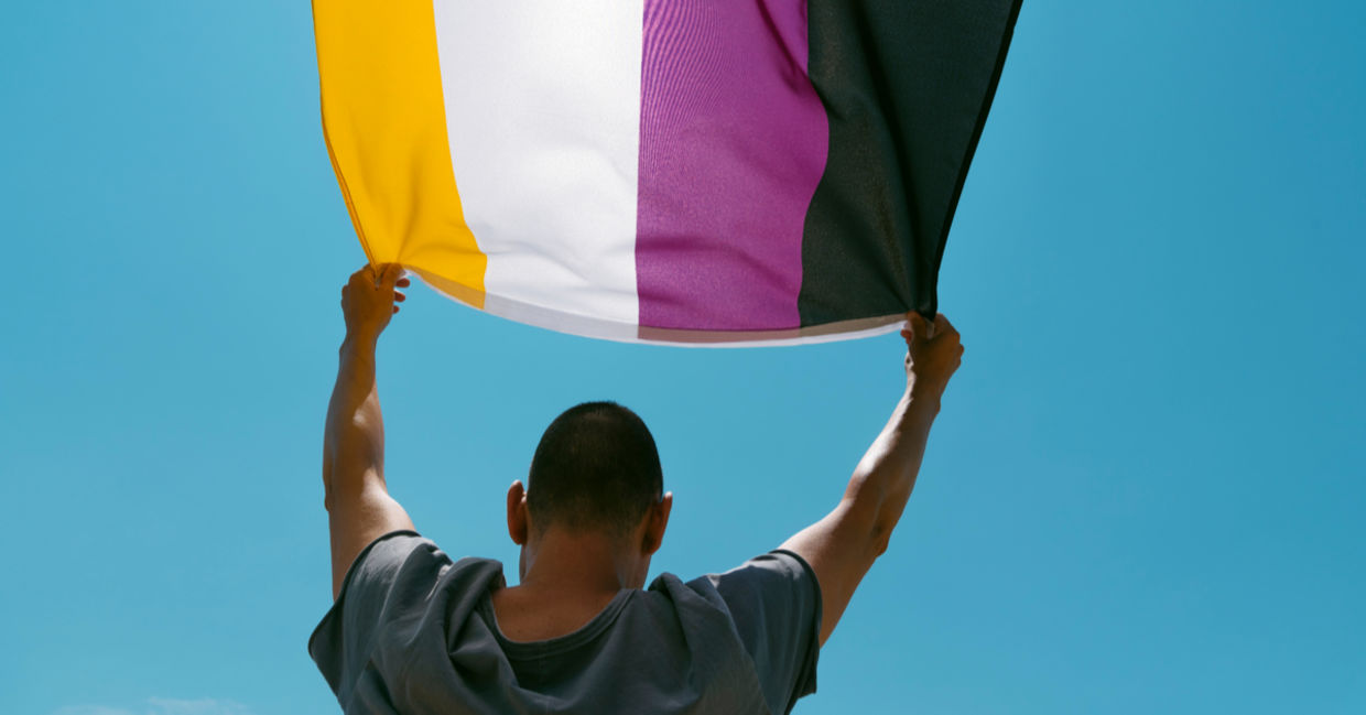 Holding up a nonbinary flag ag a Gay Pride parade. Holding up a nonbinary flag ag a Gay Pride parade.