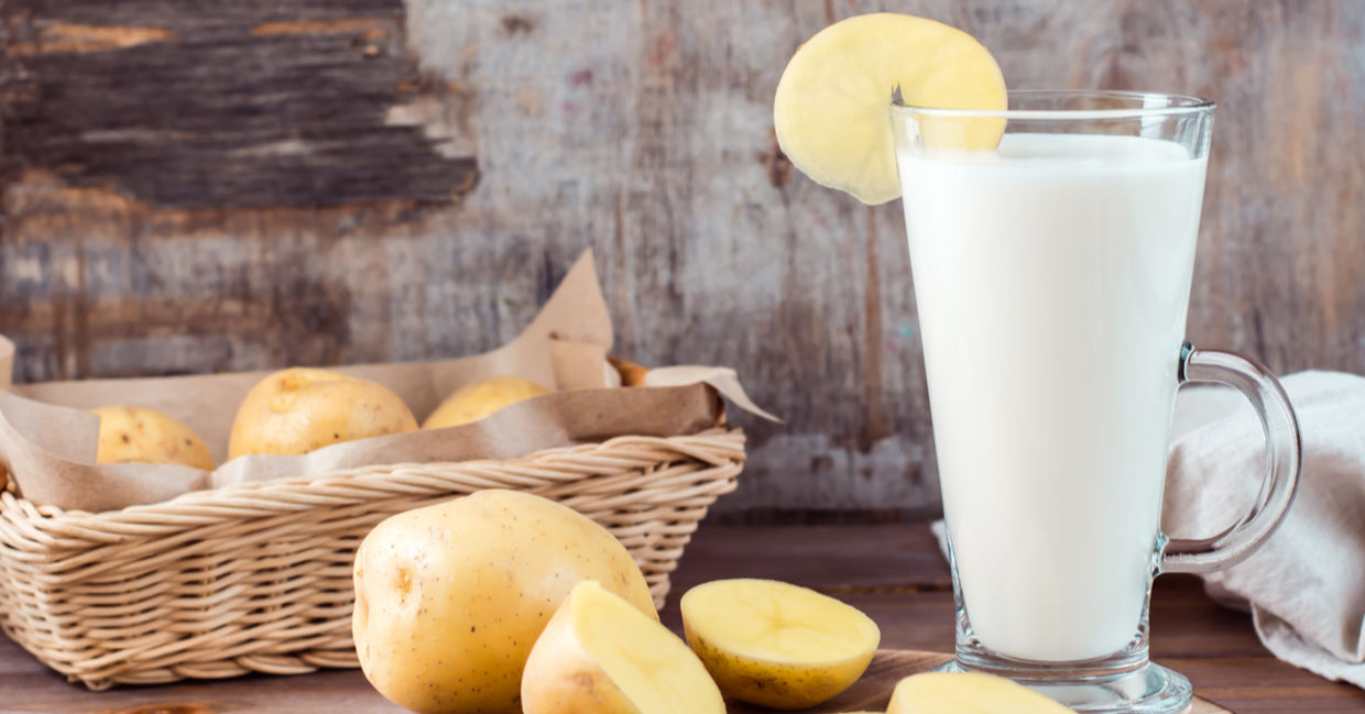 A glass of healthy potato milk is placed beside sustainable potatoes. A glass of healthy potato milk is placed beside sustainable potatoes.