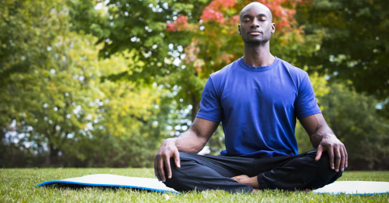 A man meditates outside on a yoga mat. A man meditates outside on a yoga mat.