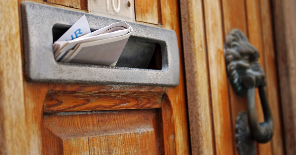 Mailbox filled with rolled spam newspaper in an old wooden door. Mailbox filled with rolled spam newspaper in an old wooden door.