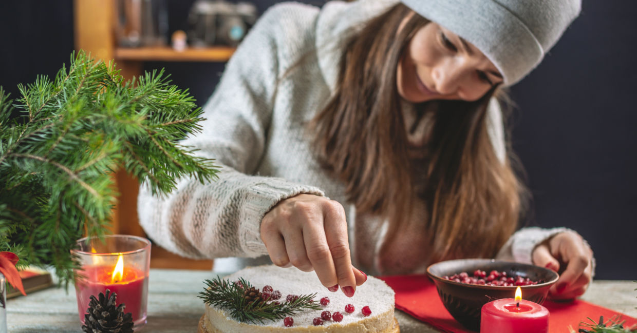 A woman decorating a festive cake with red berries. A woman decorating a festive cake with red berries.
