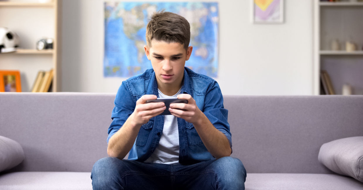 A teenager playing a game on his phone. A teenager playing a game on his phone.