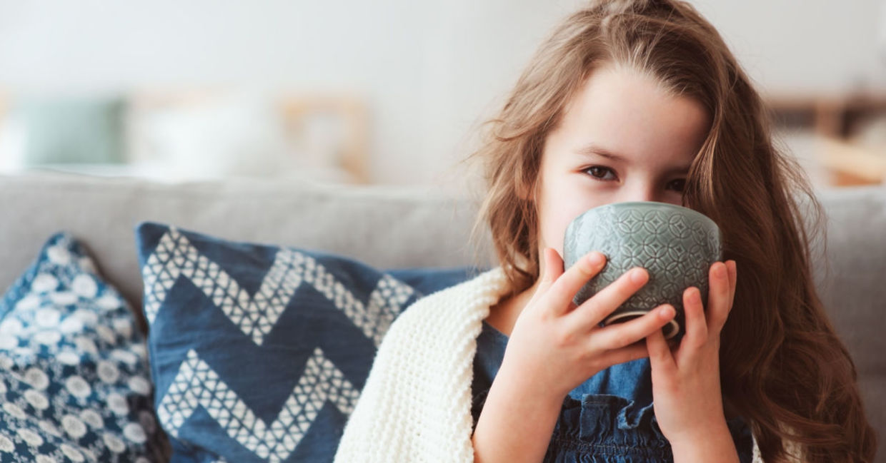 A young girl with the flu sips a hot drink. A young girl with the flu sips a hot drink.
