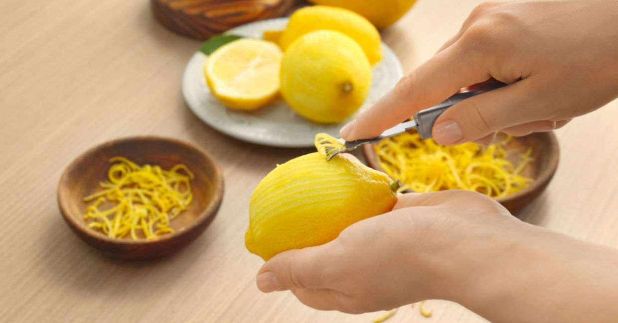 A woman peels a lemon with a zester. A woman peels a lemon with a zester.