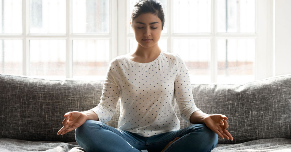 Mindful young woman sitting in lotus position while engaged in mindful yoga practice. Mindful young woman sitting in lotus position while engaged in mindful yoga practice.