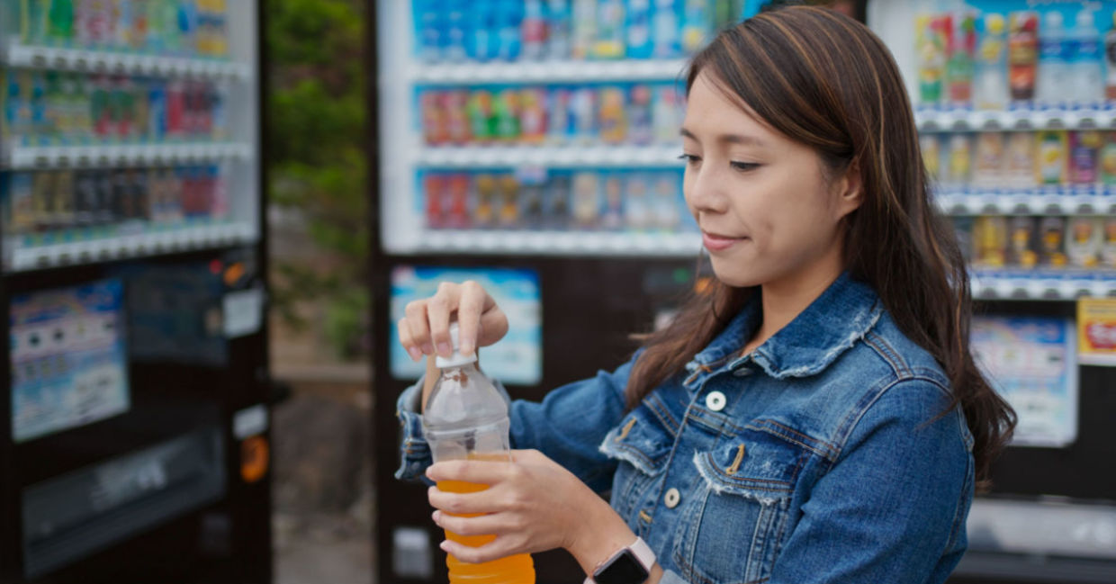 Woman purchasing a beverage from a vending machine. Woman purchasing a beverage from a vending machine.