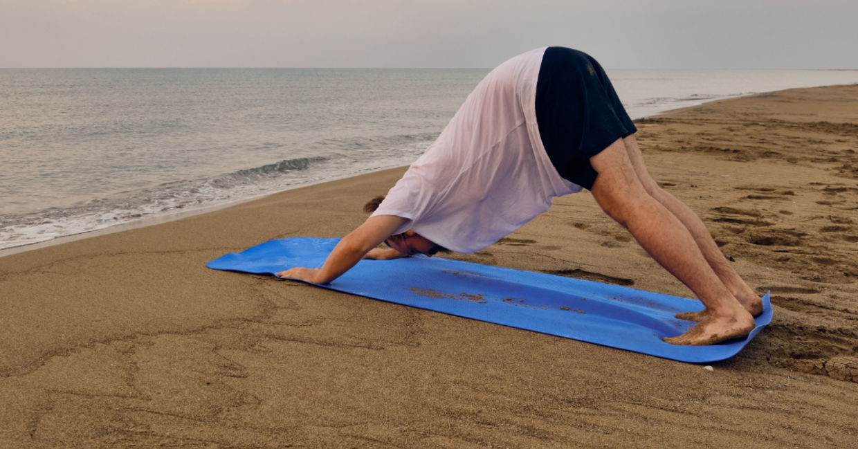 Doing the downward dog yoga pose at the beach. Doing the downward dog yoga pose at the beach.