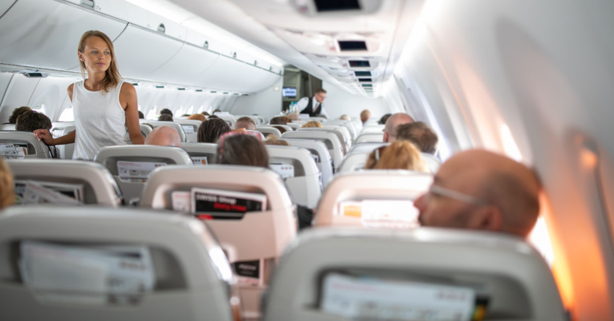 Young woman aboard an airplane walking in the aisle Young woman aboard an airplane walking in the aisle