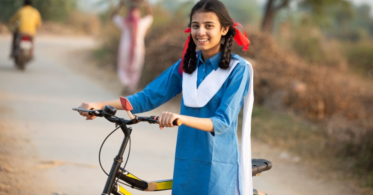 Happy schoolgirl in a rural area in India going from her village home to school, on a bicycle. Happy schoolgirl in a rural area in India going from her village home to school, on a bicycle.