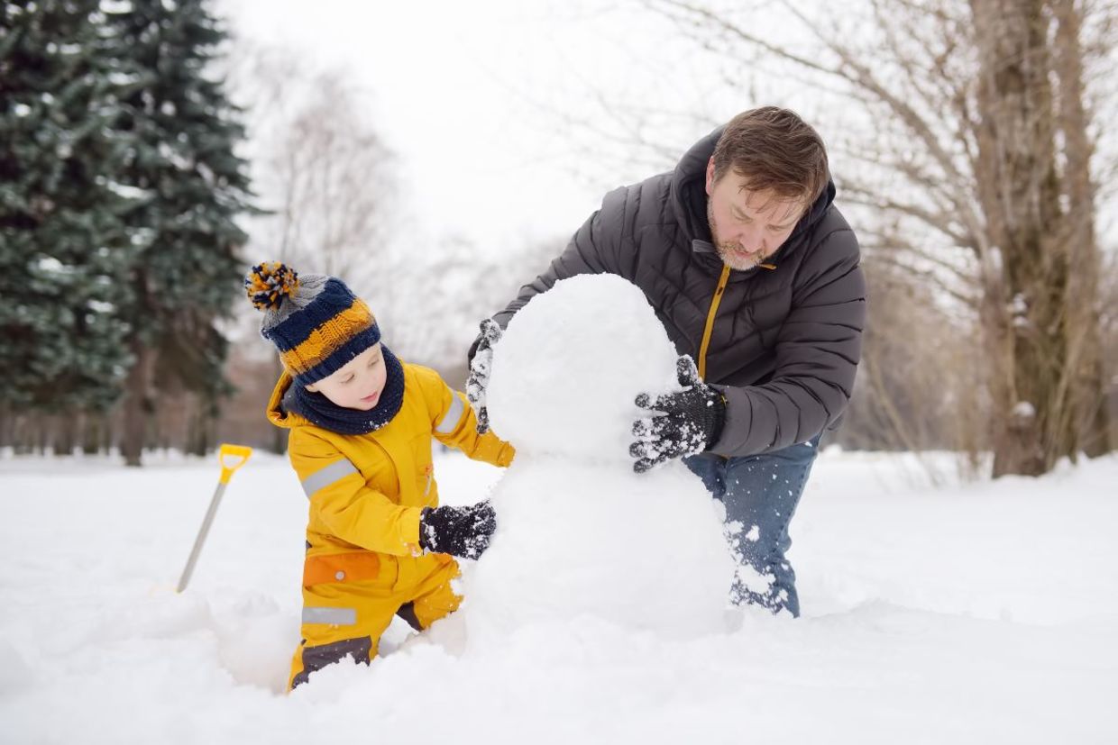 Father and son building a snowman. Father and son building a snowman.