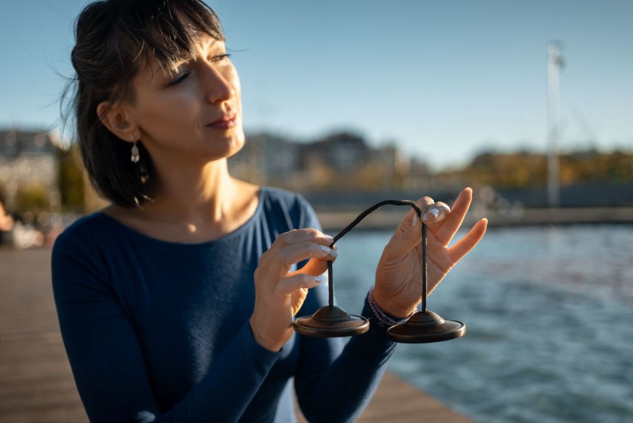 Woman holding a tingsha bell instrument for vibration. Woman holding a tingsha bell instrument for vibration.