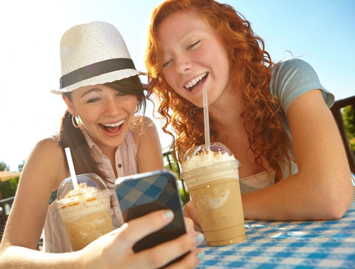 Two Gen Z friends enjoying iced coffee.