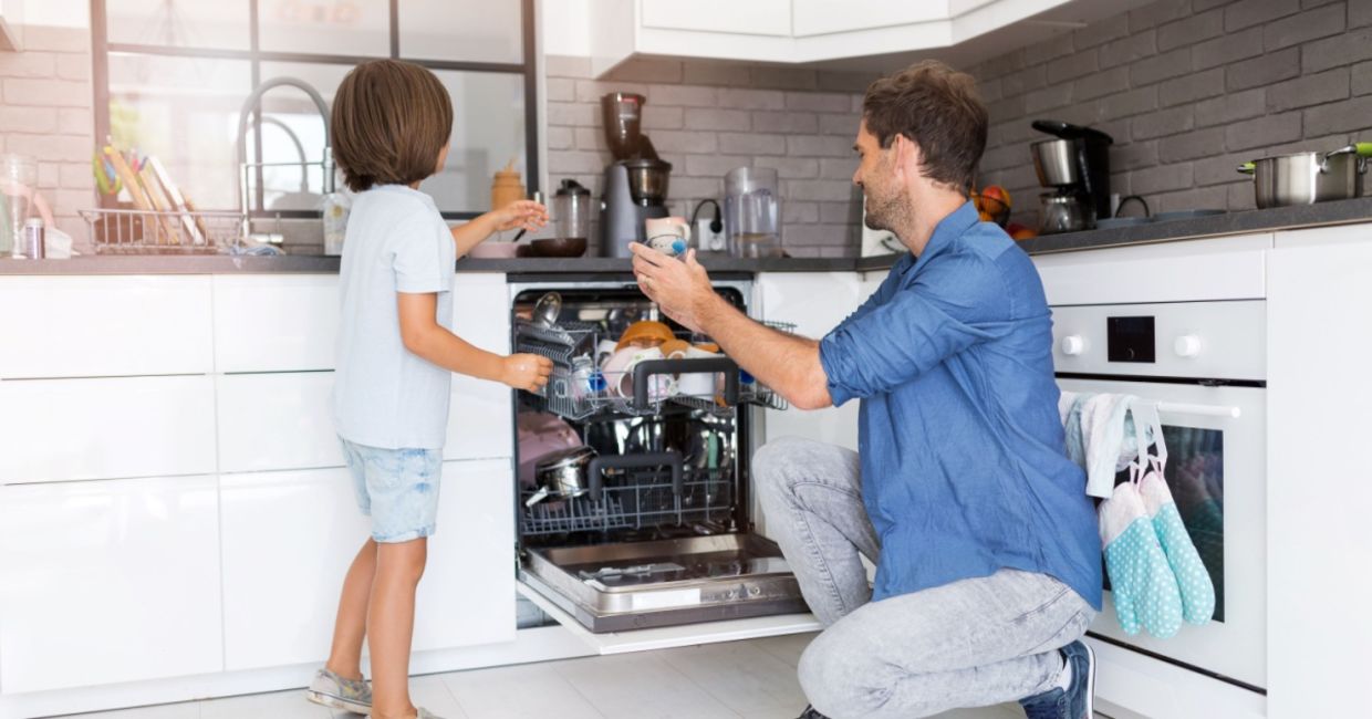 Father and son load a dishwasher. Father and son load a dishwasher.