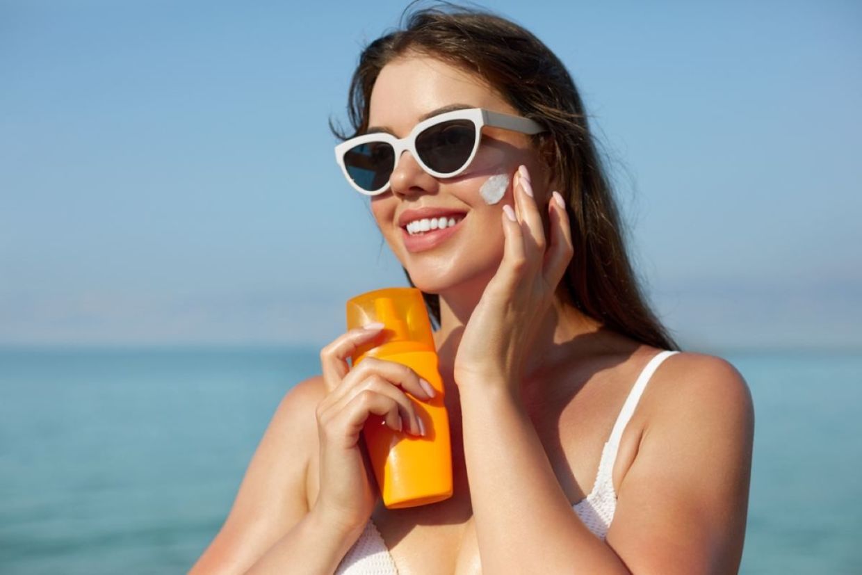 A woman puts on sunscreen on a sunny day. A woman puts on sunscreen on a sunny day.